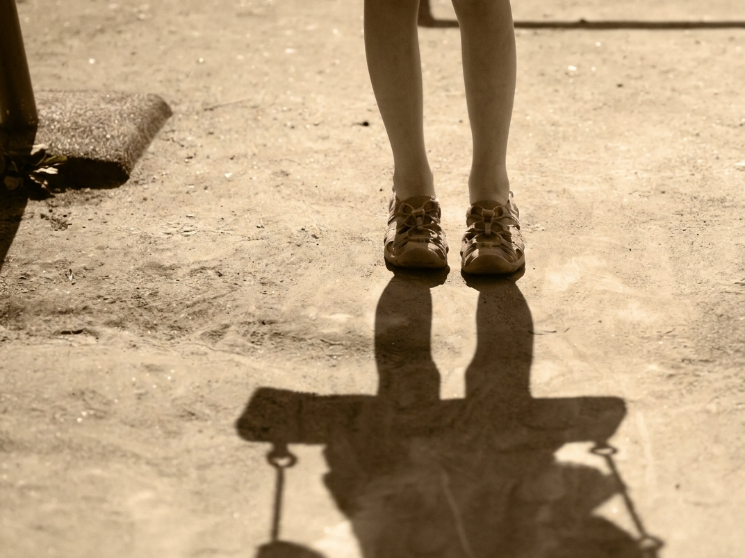 運動場の夕方。長い影が伸びている女の子